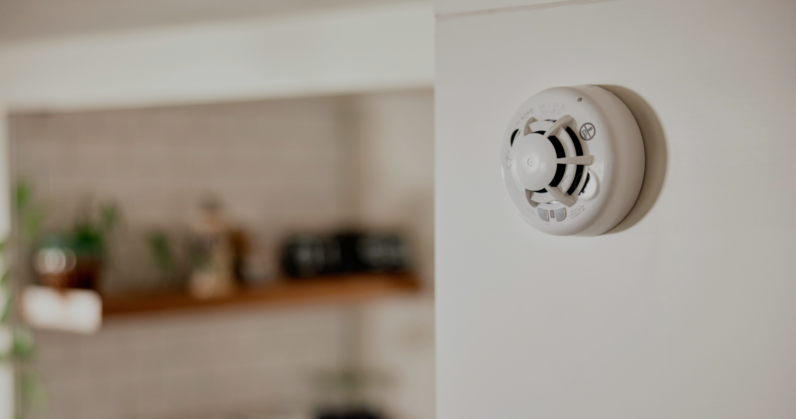 Vivint Combination Smoke and Carbon Monoxide detector installed on wall with a blurry background of the kitchen